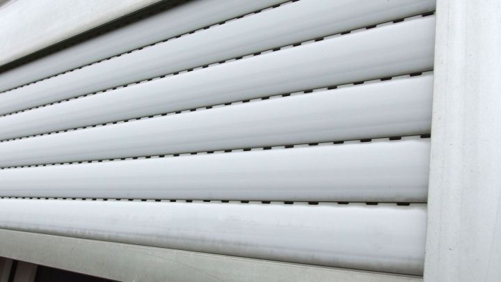 Schmutzige Jalousien sind in einem Fensterrahmen sichtbar, bereit zum Reinigen in einem hellen Raum.