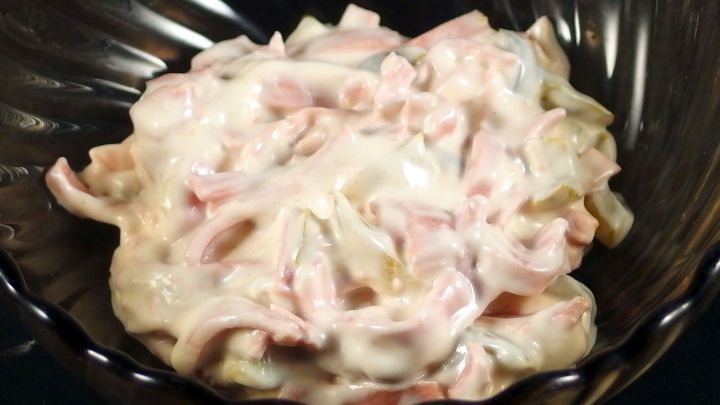 Eine cremige Mayo-Salatmischung mit Gew&uuml;rzgurken &uuml;berzogen in einer dunklen Sch&uuml;ssel, frisch angerichtet und appetitlich.