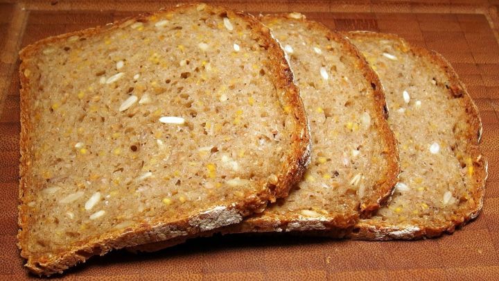 Drei Scheiben frisch geschnittenes Brot liegen auf einem Holzbrett, bereit zum Verzehr oder zur Lagerung.