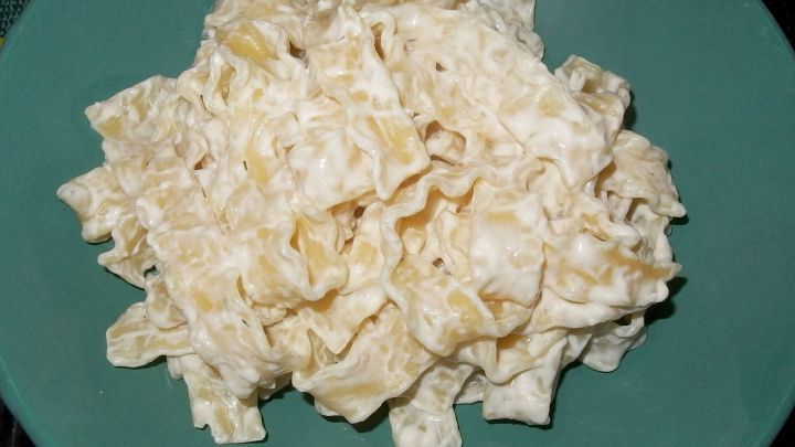 Nudeln sind auf einem gr&uuml;nen Teller angerichtet und mit cremigem Frischk&auml;se vermischt, bereit zum Servieren.