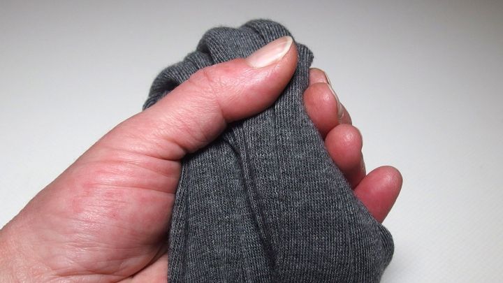 Eine Hand h&auml;lt eine graue Kinderstrumpfhose fest, w&auml;hrend der Fokus auf der Verwendung von Strumpfhosen liegt.