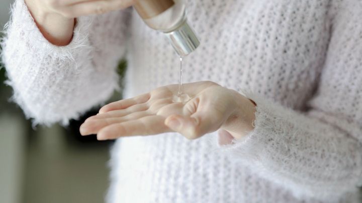 Eine Person mit einem weichen, flauschigen Pullover gie&szlig;t mildes Haarshampoo in die Handfl&auml;che, um es als Seife zu verwenden.