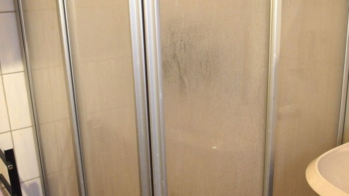 Eine Glasduschabtrennung steht im Badezimmer und zeigt beschlagene, durchsichtige Scheiben, die die Dusche abtrennen.