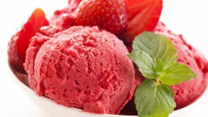 Erdbeersorbet in einer wei&szlig;en Schale, garniert mit frischen Erdbeeren und einem Minzblatt, vor neutralem Hintergrund.