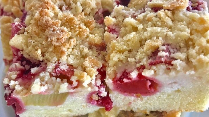 Saftiger Rhabarberkuchen mit Banane liegt auf einem Teller, in mundgerechte St&uuml;cke geschnitten und mit Streuseln garniert.