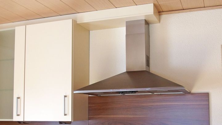 Stark verschmutzte K&uuml;chenschr&auml;nke mit einer Dunstabzugshaube, die auf ein sauberes Umfeld ausgerichtet ist.