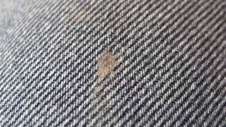 Ein Fleck auf grauem Stoff zeigt, wie Gallseife als effektiver Fleckenkiller eingesetzt werden kann.