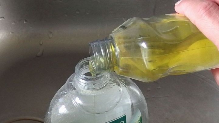 Eine Hand dosiert sparsames Sp&uuml;lmittel aus einer Flasche in einen Beh&auml;lter &uuml;ber einem Sp&uuml;lbecken.