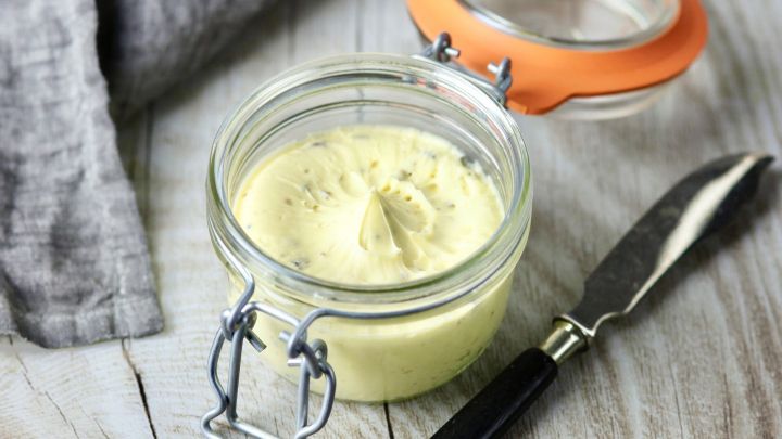 Ein elegantes Glas mit hausgemachtem Dip steht auf einem Holzuntergrund, daneben liegt ein Messer f&uuml;r den Servierbedarf.