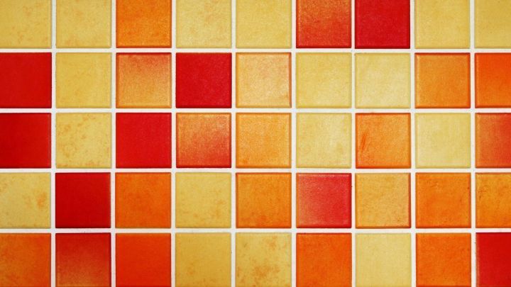 Bunte Fliesen mit orange, gelben und roten Mustern bilden die Oberfl&auml;che, die f&uuml;r die Reinigung von Schimmelfugen genutzt wird.