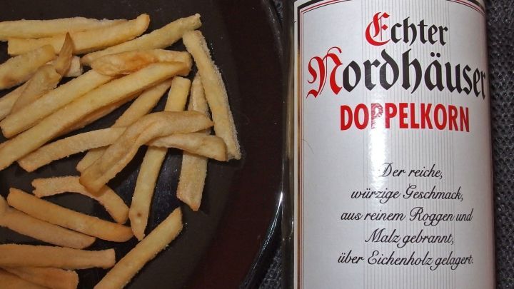 Frittierte Pommes frites liegen neben einer Flasche Doppelkorn, um den Kater nach dem Alkohol zu bek&auml;mpfen.