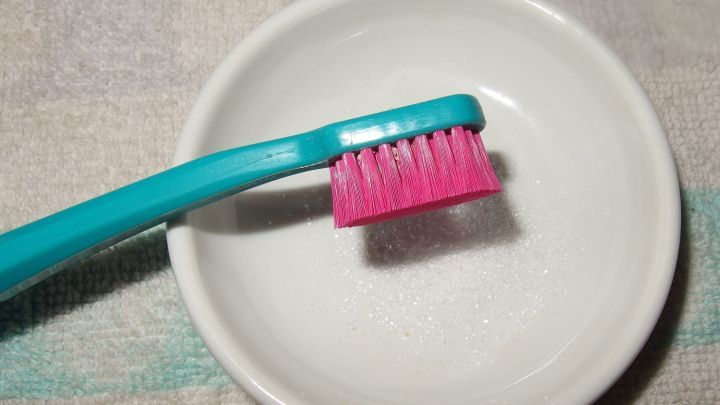Eine Zahnb&uuml;rste mit pinkem Borstenkopf steht in einer wei&szlig;en Sch&uuml;ssel, die m&ouml;glicherweise Zahnstein entfernt und Zahnfleischbluten verhindert.