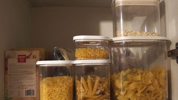 Gl&auml;ser mit verschiedenen Teigwaren stehen ordentlich in einem K&uuml;chenschrank, um Lebensmittelmotten zu verhindern.