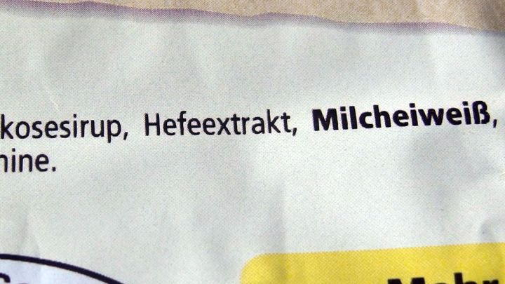 Die Verpackung zeigt Inhaltsstoffe, darunter "Milcheiwei&szlig;", w&auml;hrend Verbraucher &uuml;ber Geschmacksverst&auml;rker informiert werden.