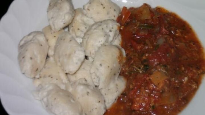 Zarte Frischk&auml;se-Gnocchi liegen auf einem Teller neben einer w&uuml;rzigen Tomatenso&szlig;e, bereit zum Servieren.