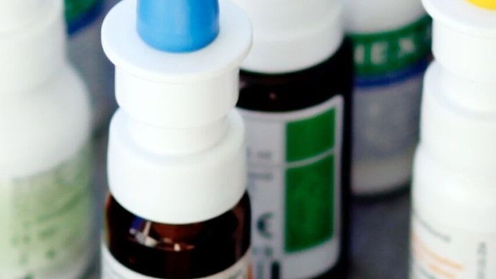 Eine Reihe von Nasensprays steht auf einer Oberfl&auml;che, w&auml;hrend das blaue Spray im Vordergrund hervorsticht.