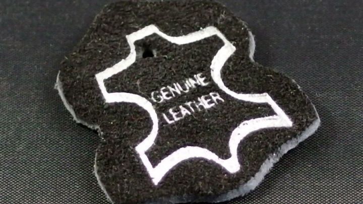 Ein schwarzes Pflegepad in Lederform zeigt den Text „GENUINE LEATHER“, das zur Lederpflege verwendet wird.