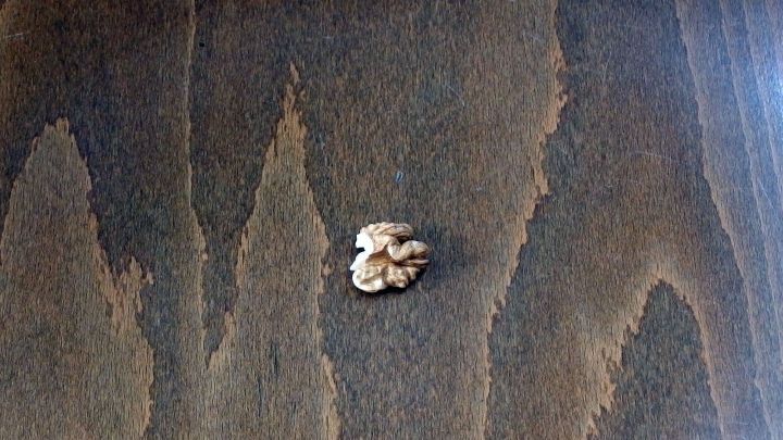 Auf dem Laminat befindet sich eine Walnuss, die zur Entfernung von Kratzern verwendet wird. Der Hintergrund zeigt eine dunkle Holzoberfl&auml;che.