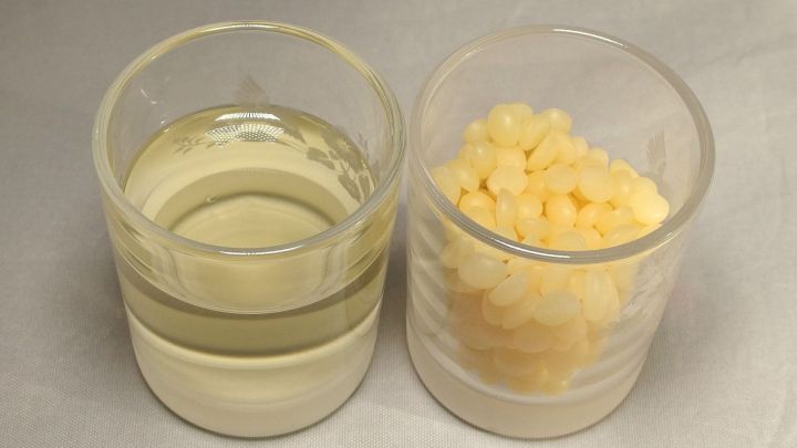 Zwei Beh&auml;lter stehen nebeneinander: einer mit klarem, pflegendem Fl&uuml;ssigkeit und einer mit gelben Wachsperlen zur Lederpflege.