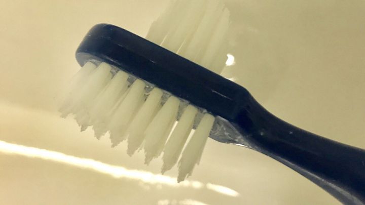 Eine B&uuml;rste liegt in einer Sp&uuml;le, w&auml;hrend ihre Borsten nah am Ablauf sind, bereit f&uuml;r verschiedene Reinigungsaufgaben.