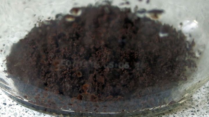 Ein Glas mit Kaffeesatz liegt auf einer Arbeitsplatte, bereit zum Reinigen von Flaschen und Vasen.