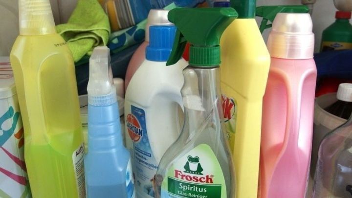 Bunte Flaschen mit Putzmitteln stehen eng zusammen in einem Putzschrank und warten auf ihre Verwendung beim Reinigen.