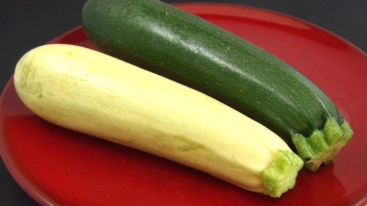Zucchinis liegen auf einem roten Teller, eine gelbe und eine gr&uuml;ne, bereit zum Kochen oder als frisches Gem&uuml;se.