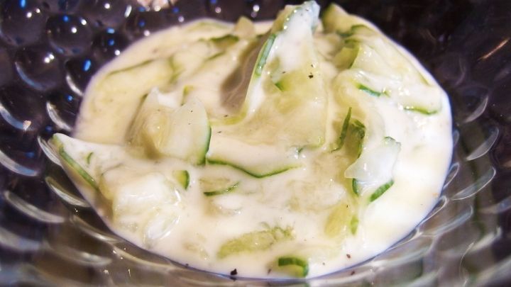 Gurkensalat liegt in einer Sch&uuml;ssel und ist mit einem cremigen Joghurt-Dill-Dressing &uuml;berzogen, erfrischend und appetitlich.