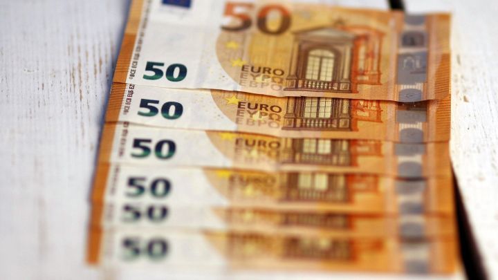 Vier f&uuml;nfzig Euro-Scheine liegen ordentlich auf einem hellen Holztisch, was Sparen beim Einkaufen symbolisiert.