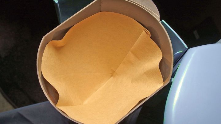 Ein Kaffeefilter der Gr&ouml;&szlig;e 2 liegt flach in einem braunen Filterhalter, bereit zum Kaffeebr&uuml;hen in einer modernen K&uuml;che.