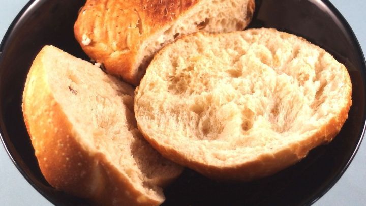 Halbierte, frische Br&ouml;tchen liegen in einer schwarzen Sch&uuml;ssel, bereit zum Essen oder f&uuml;r kreative Sparl&ouml;sungen.