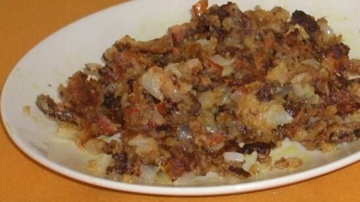 Ein gef&uuml;llter Teller mit gebratenen Resten, liegt auf einem orangefarbenen Tisch, umgeben von einem gr&uuml;n-gelben K&uuml;chentuch.