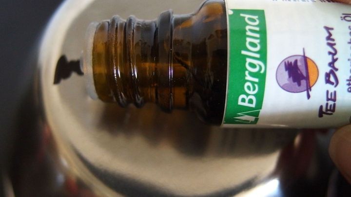 Ein brauner Flaschenhals h&auml;lt ein L&ouml;sungsmittel &uuml;ber einer glatten, metallischen Oberfl&auml;che, um wasserfesten Edding zu l&ouml;sen.