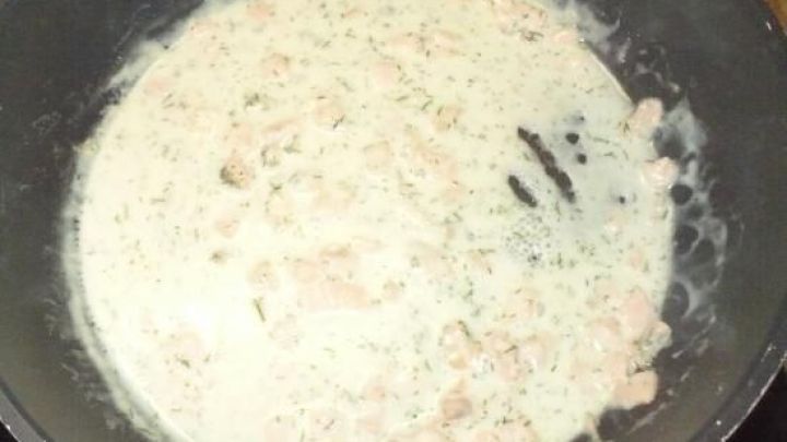 In einer Pfanne k&ouml;chelt eine cremige R&auml;ucherlachs-Sahnesauce, die bereit ist, &uuml;ber Pasta serviert zu werden.