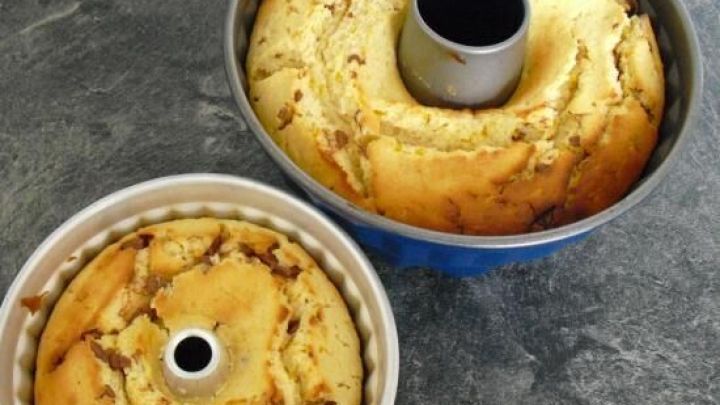 Ein R&uuml;hrkuchen mit Sekt, Mandarinen und Kokosflocken, frisch aus zwei Backformen auf einer dunklen Arbeitsfl&auml;che.