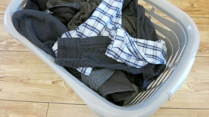 Ein W&auml;schekorb mit schmutziger W&auml;sche liegt auf einem Holzboden, bereit zum Waschen bei Bedarf.