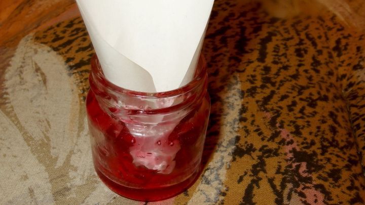 Ein Glas mit Marmelade steht auf einem Tisch, w&auml;hrend ein Papiertrichter es kreativ als Fliegenfalle nutzt.