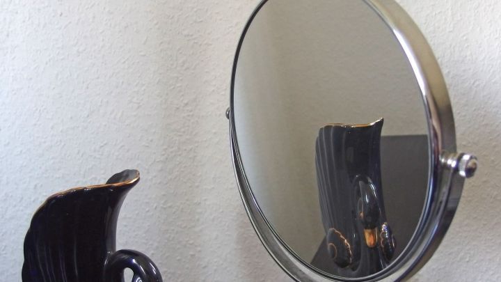 Ein runder Spiegel steht auf einem Tisch, reflektiert Umgebungen und wird ohne Glasreiniger gereinigt.