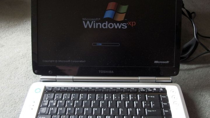 Ein Laptop zeigt den Startbildschirm von Windows XP. Er liegt auf dem Boden und k&ouml;nnte Hitze auf Oberschenkel &uuml;bertragen.