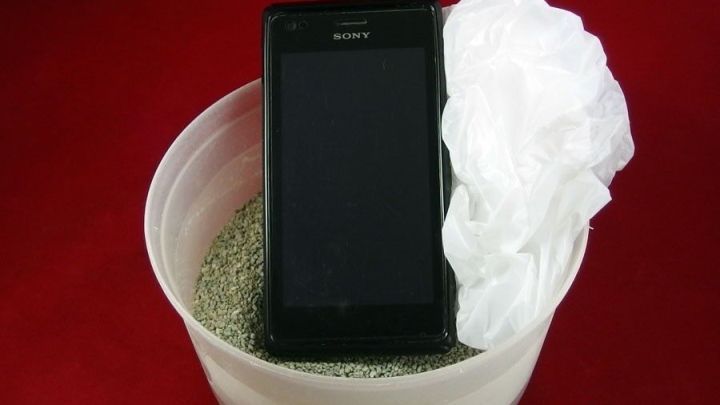 Ein Handy steht in einer Sch&uuml;ssel mit Katzenstreu, um es nach Wasserschaden mit einem Plastikbeutel zu retten.