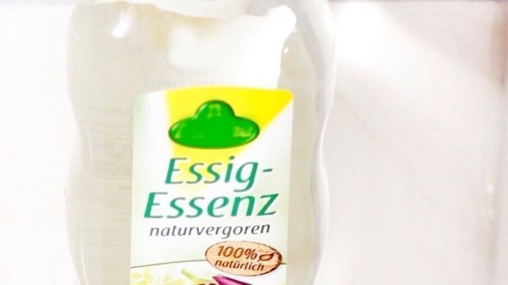 Ein Fl&auml;schchen Essig-Essenz steht auf einer hellen Oberfl&auml;che, bereit zur Anwendung gegen Kopfschmerzen mit einem Essigumschlag.