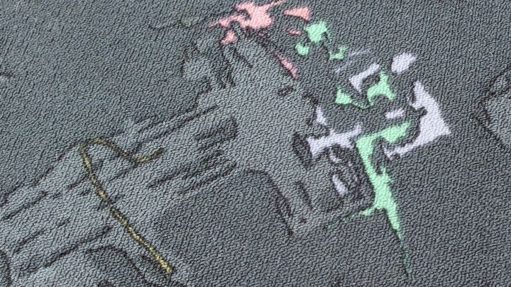 Ein Teppich zeigt erbrochenes Material in verschiedenen Farben, das unsch&ouml;n auf der Oberfl&auml;che verteilt ist.