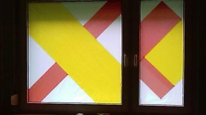 Bunte Seidenpapierstreifen dienen als Sichtschutz im Fenster, um Privatsph&auml;re in einem dunklen Raum zu gew&auml;hrleisten.