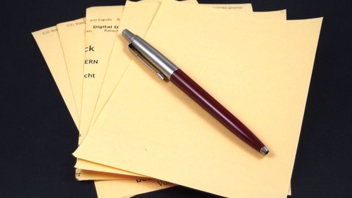 Staples of gelbes Papier liegen gestapelt, w&auml;hrend ein Schreibstift daneben liegt, bereit zum Notieren von Tipps zum Papier sparen.