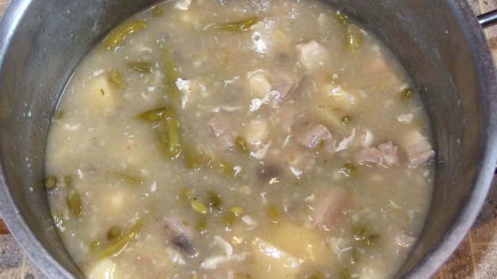 Ein gro&szlig;er Topf mit einem Eintopf, der fleischige Zutaten und Gem&uuml;se in einer s&auml;migen Br&uuml;he vereint, steht auf einer K&uuml;chenoberfl&auml;che.