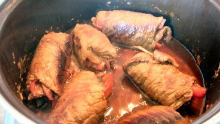 Rouladen k&ouml;cheln in einem Topf in dunkler So&szlig;e, die Umgebung ist eine K&uuml;che.