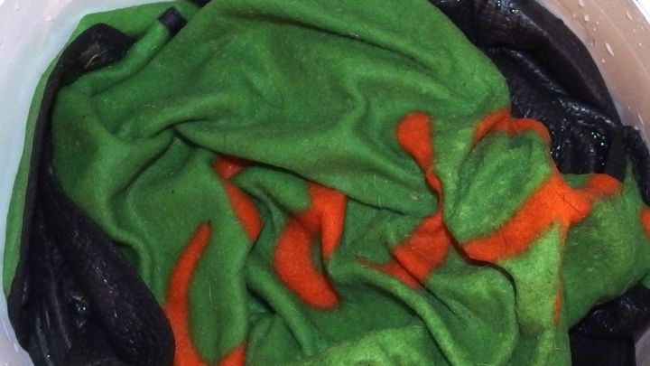 Ein hoher Berg aus bunten, verf&auml;rbten Handt&uuml;chern liegt in einer schwarzen Wanne, die bereit f&uuml;r die Waschgange ist.