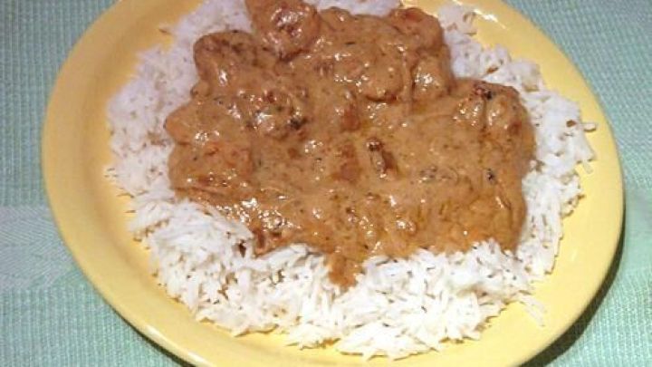 Garnelen in einer cremigen Limetten-Sahne-So&szlig;e liegen auf einem Bett aus wei&szlig;em Reis, serviert auf einem gelben Teller.