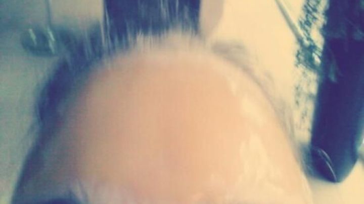 Eine Person mit einer honigfarbenen Gesichtsmaske zu sehen, die auf der Stirn aufgetragen ist, im Hintergrund ein moderner Raum.