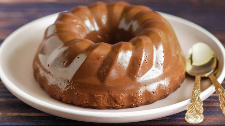 Ein schokoladiger Schokopudding liegt auf einem wei&szlig;en Teller, umgeben von einem rustikalen Holzuntergrund. Anfrage, um den Pudding zu genie&szlig;en.